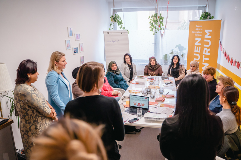 Frauenversammlung in einem modernen Raum zur Förderung von Integration und Unterstützung.