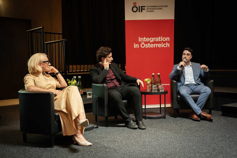 Mann hält Ansprache am Rednerpult mit Mikrofon vor Publikum