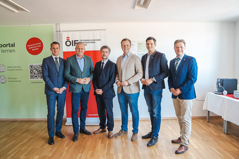 Sechs männliche Fachleute stehen vor ÖIF und Deutsch-Lern-Schild