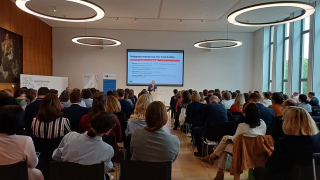 Eine Präsentation über Integrationsservices für Fachkräfte vor einem großen Publikum.