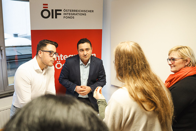 Menschen im Gespräch vor OIF-Logo.