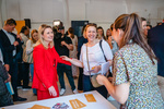 Frauen unterhalten sich freundlich bei einer Veranstaltung, mehrere Personen sind im Hintergrund zu sehen.