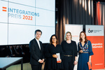 Verleihung des Integrationspreises 2022, vier Personen stehen auf der Bühne neben einem großen Bildschirm.