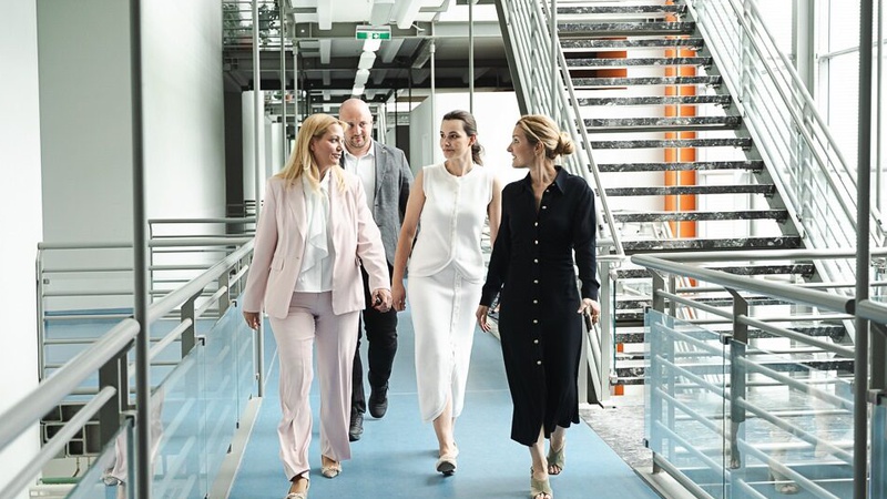 Vier Personen in Business-Kleidung gehen durch modernen Flur