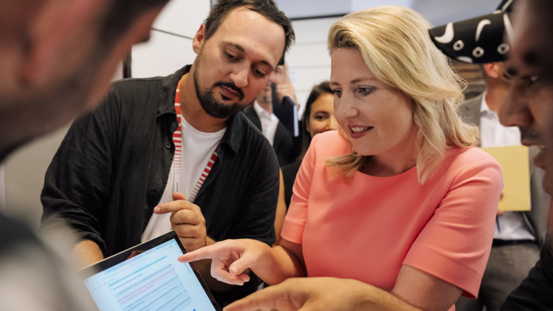 Eine Gruppe von Menschen schaut auf einen Laptop, während sie miteinander diskutieren.