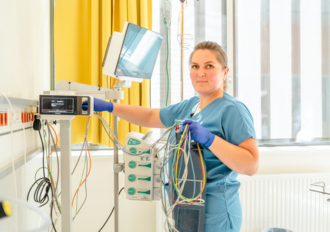 Eine Pflegekraft in blauer Kleidung hält Kabeln