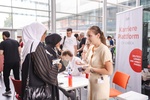 Zwei Frauen sprechen mit einer Mitarbeiterin an einem Informationsstand zur Karriereplattform.