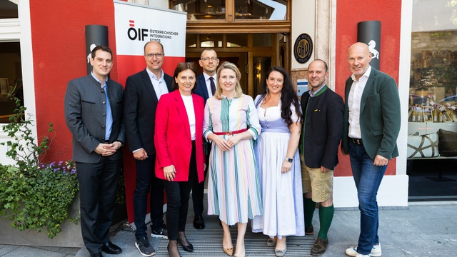Gruppenfoto von Personen vor einem roten Gebäude mit einem Banner des Österreichischen Integrationsfonds.