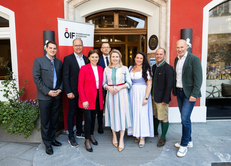 Gruppenfoto von Personen vor einem roten Gebäude mit einem Banner des Österreichischen Integrationsfonds.