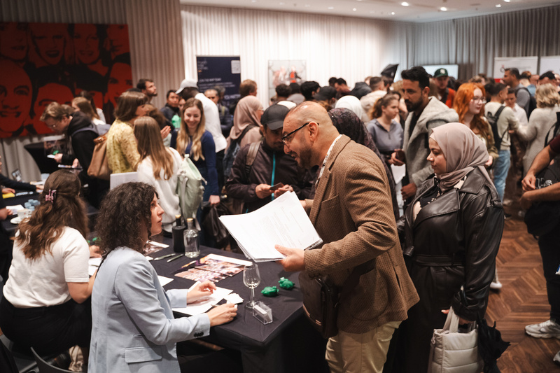 Eine lebhafte Versammlung von Menschen, die miteinander sprechen und an Ständen Informationen austauschen.