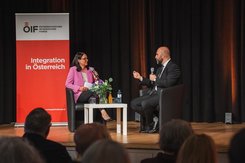 Zwei Personen sitzen auf der Bühne und diskutieren über Integration in Österreich.