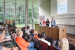 Zwei Referenten präsentieren auf einer Veranstaltung vor einem Publikum in einem modernen Saal.