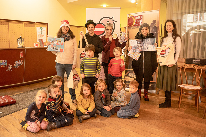 Gruppenfoto von Erwachsenen und Kindern, die Bücher und Spielzeug in einer Einrichtung präsentieren.