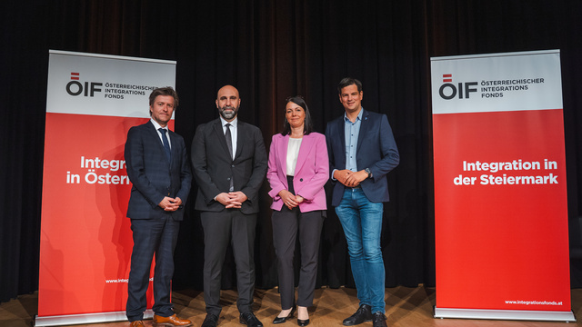 Vier Personen stehen neben Bannern des Österreichischen Integrationsfonds, die das Thema Integration behandeln.
