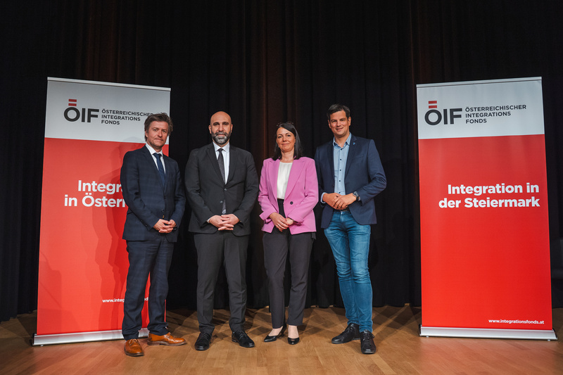 Vier Personen stehen neben Bannern des Österreichischen Integrationsfonds, die das Thema Integration behandeln.
