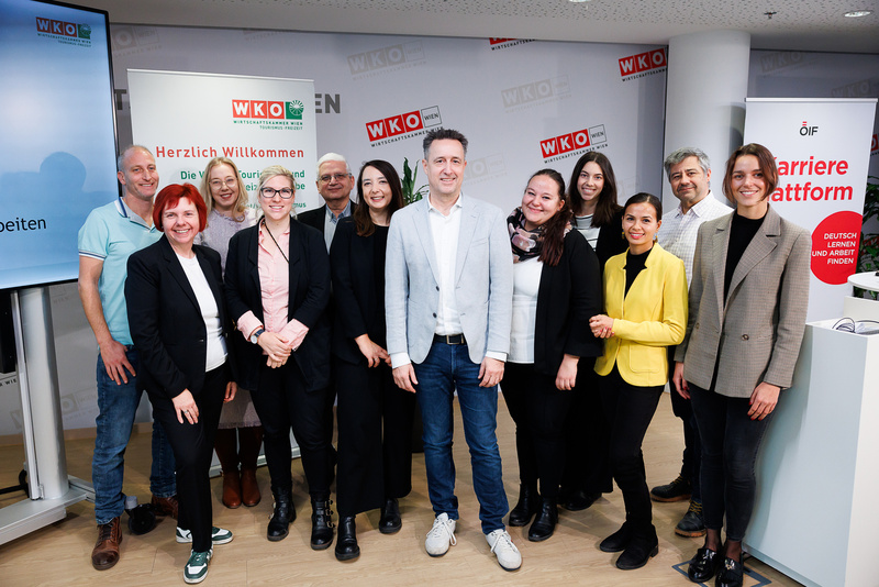 Gruppe von Personen bei einer Veranstaltung zur Karriere und Weiterbildung, mit Willkommensschildern im Hintergrund.