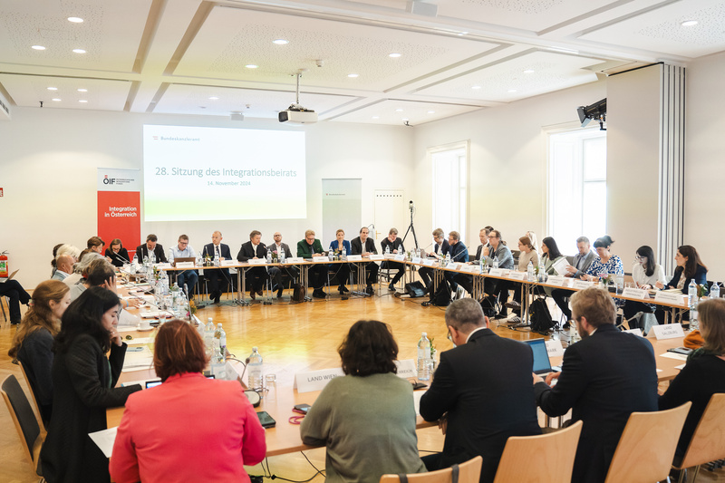 Sitzung des Integrationsbeirats mit Teilnehmern an einem langen Tisch in einem hellen Raum.