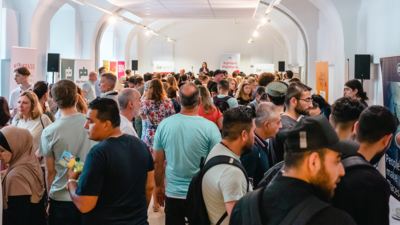 Menschen stehen in einem langen Raum zusammen, diskutieren und interagieren bei einer Veranstaltung.