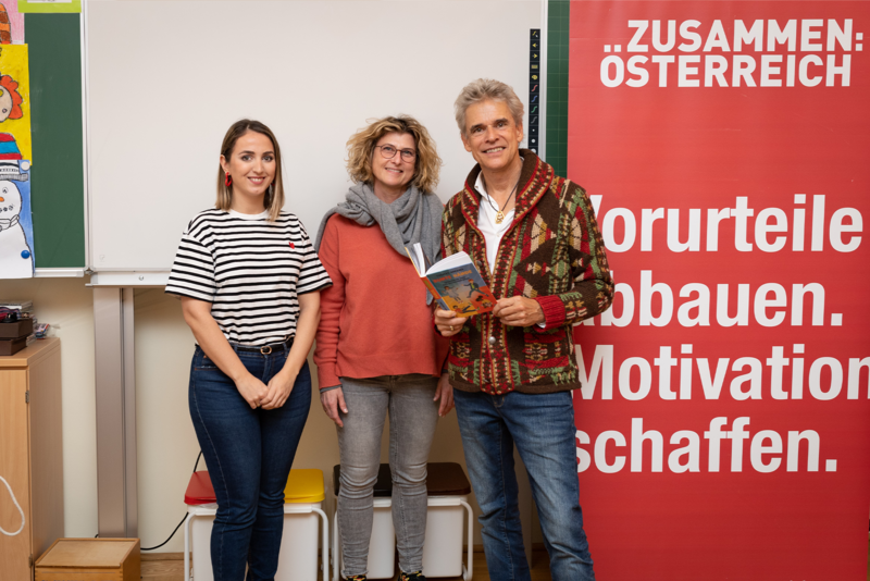 Drei Personen stehen vor einer Wand mit einem roten Banner über Vorurteile und Motivation.