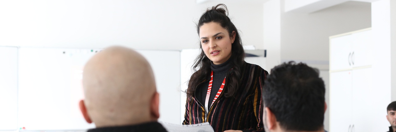 Frau spricht vor einem Publikum in einem Raum.