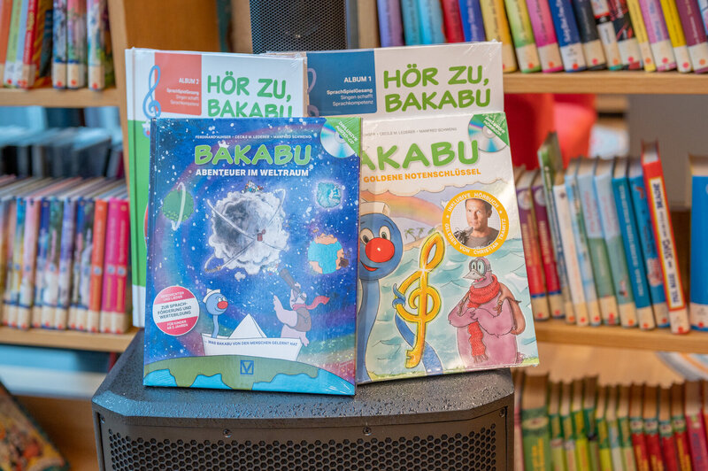 Zwei Kinderbücher mit dem Titel "Bäkabu" über Abenteuer im Weltraum und goldene Notenschlüssel stehen auf einem Tisch.