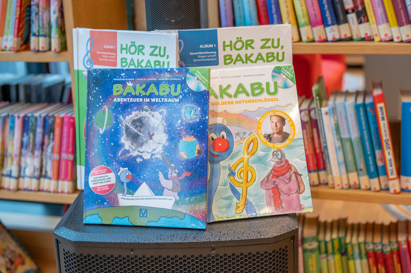 Zwei Kinderbücher mit dem Titel "Bäkabu" über Abenteuer im Weltraum und goldene Notenschlüssel stehen auf einem Tisch.