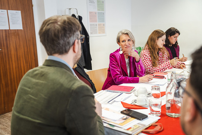 Gruppendiskussion mit mehreren Personen am Tisch.