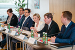 Eine Gruppe von Personen diskutiert an einem Tisch während einer Konferenz, mit Getränken und Unterlagen vor ihnen.