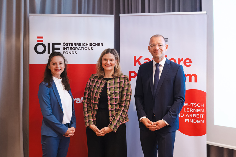 Drei Personen stehen vor Fahnen des Österreichischen Integrationsfonds bei einer Veranstaltung zur Karriereförderung.