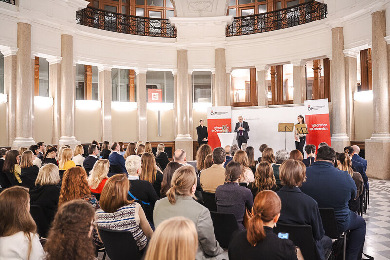 Veranstaltung mit Publikum und Rednern in einem Saal.
