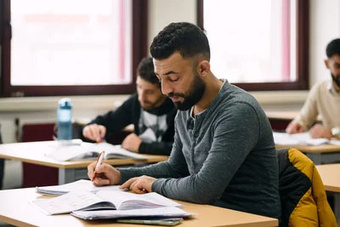 Lernende Männer in einem Klassenzimmer beim Schreiben.