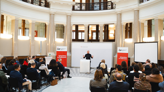 Veranstaltung mit Vortragendem vor Publikum in einem Saal.