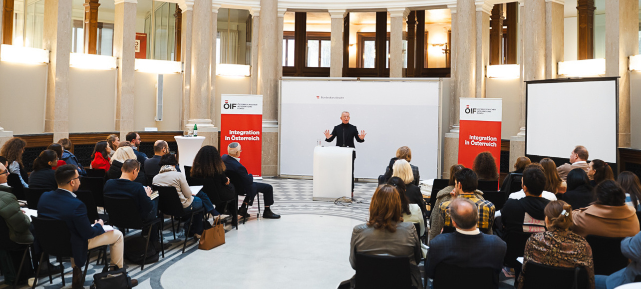 Veranstaltung mit Vortragendem vor Publikum in einem Saal.