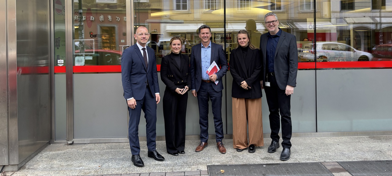 Gruppenfoto vor dem Integrationszentrum Kärnten mit fünf Personen in formeller Kleidung.