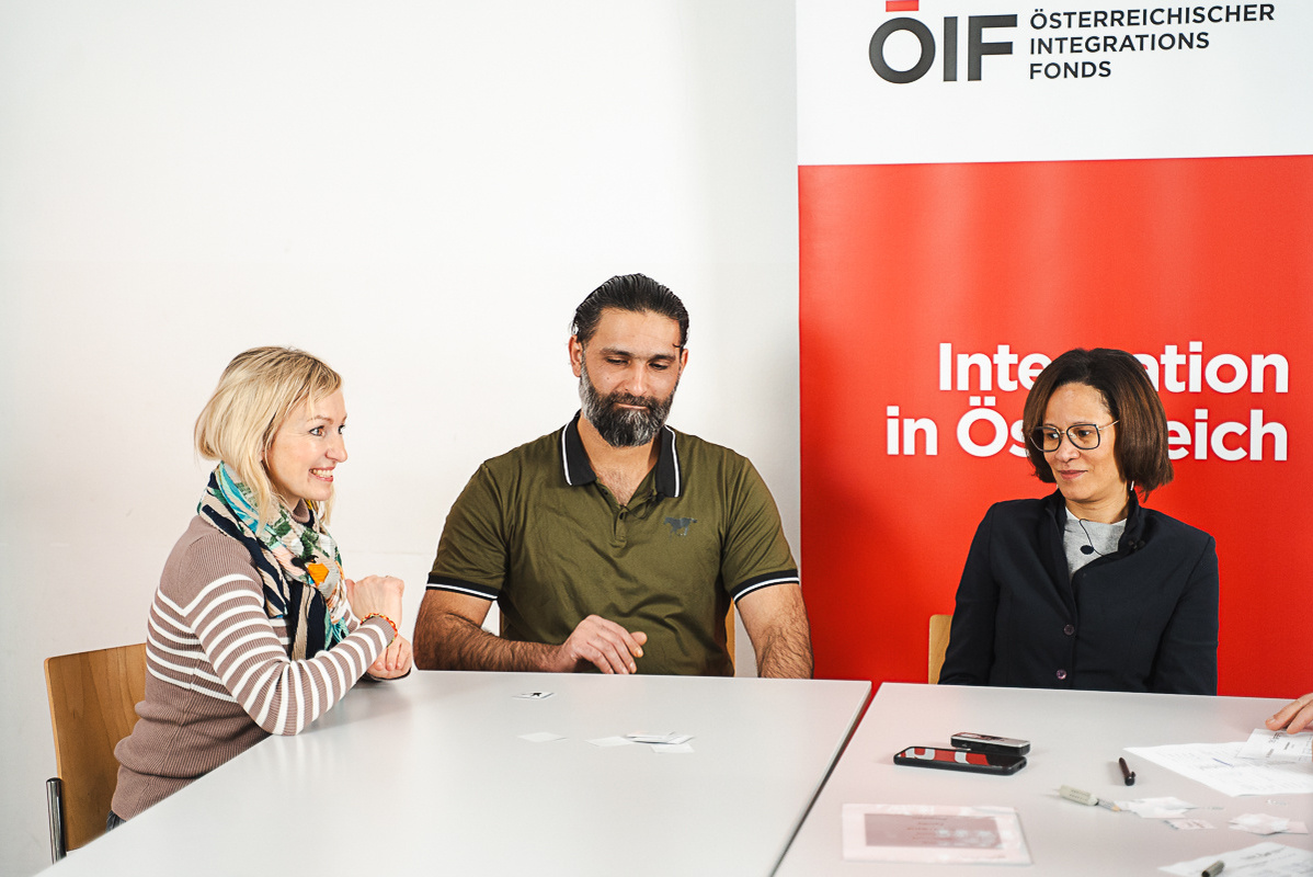 Drei Personen an einem Tisch, eine Deutschprüfung wird abgehalten