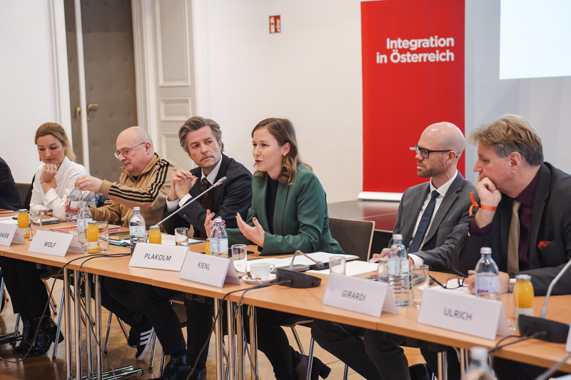 Eine Diskussionsrunde zu Integration in Österreich mit mehreren Teilnehmern am Tisch.