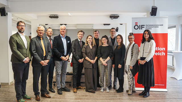 Eine Gruppe von zwölf Personen steht in einem Raum neben einem Banner des Österreichischen Integrationsfonds.