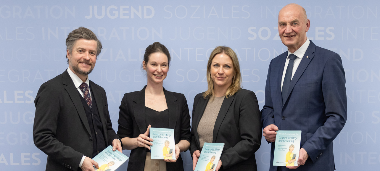 Vier Personen halten Broschüren in der Hand.