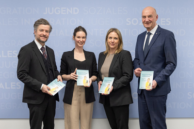 Vier Personen halten Broschüren in der Hand.