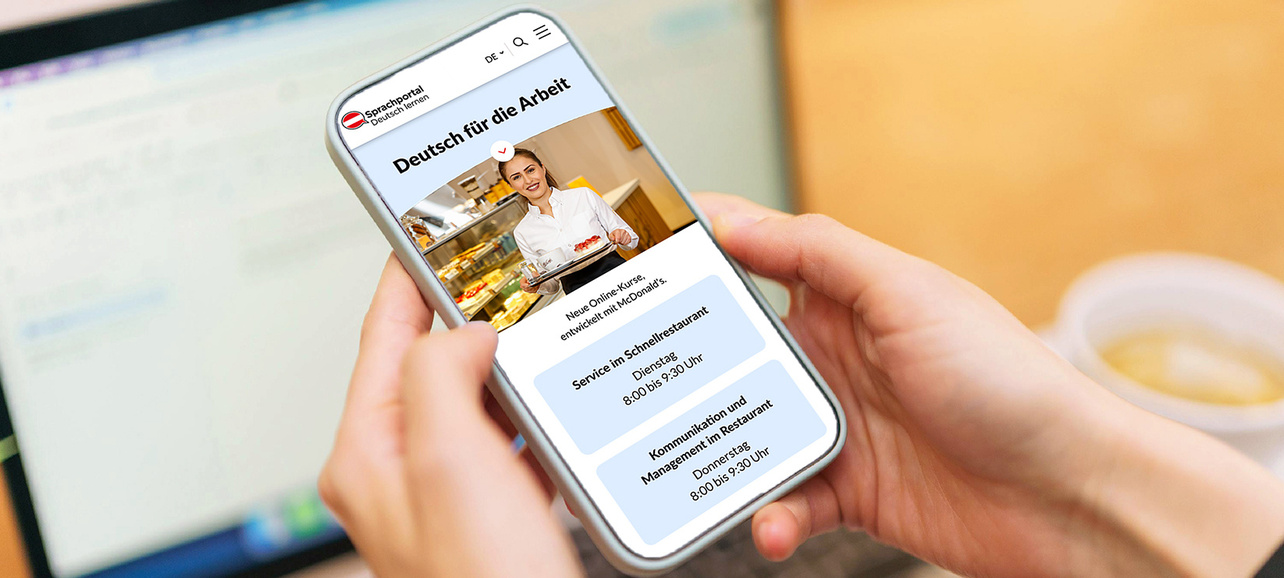 Eine Person hält ein Smartphone auf dem das Modul "Deutsch für die Arbeit" von Sprachportal.at abgebildet wird