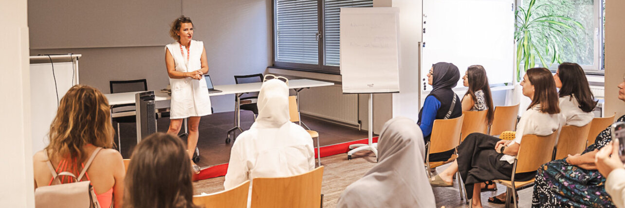 Eine Frau steht vor einer Gruppe Workshopteilnehmerinnen