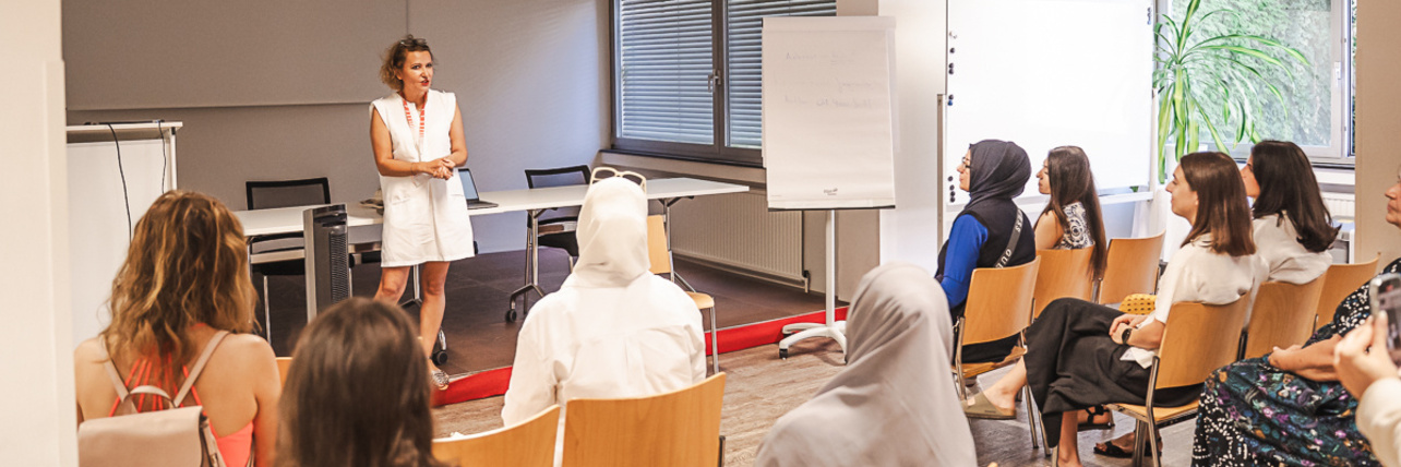 Eine Frau steht vor einer Gruppe Workshopteilnehmerinnen