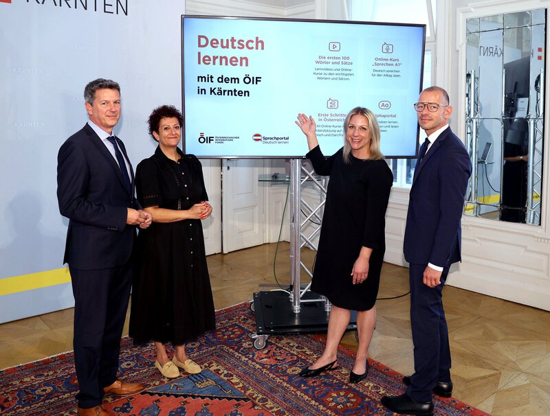 Vier Personen vor großem Bildschirm zur Deutschlern-Präsentation