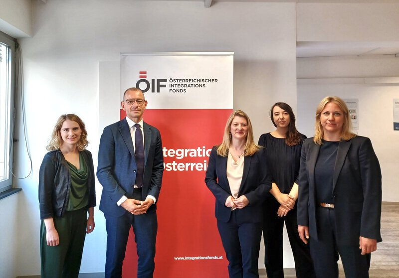 Fünf Fachleute vor ÖIF-Integrationsfonds-Logoschrift