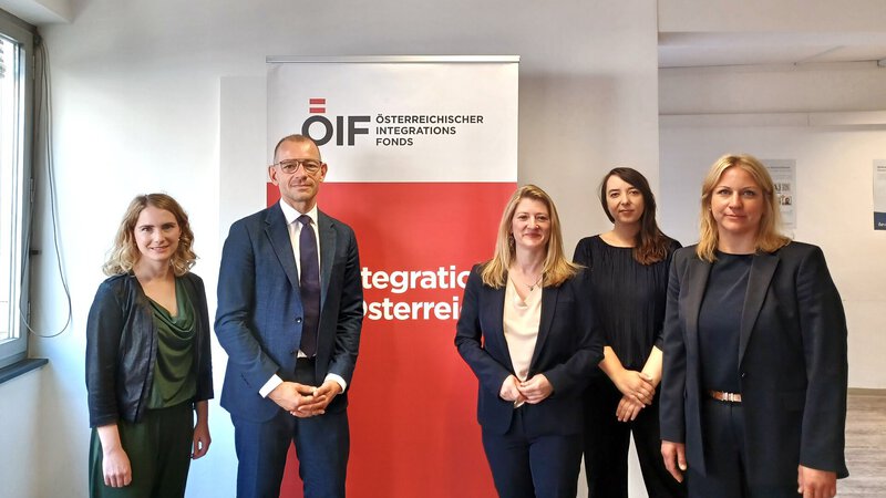 Fünf Fachleute vor ÖIF-Integrationsfonds-Logoschrift