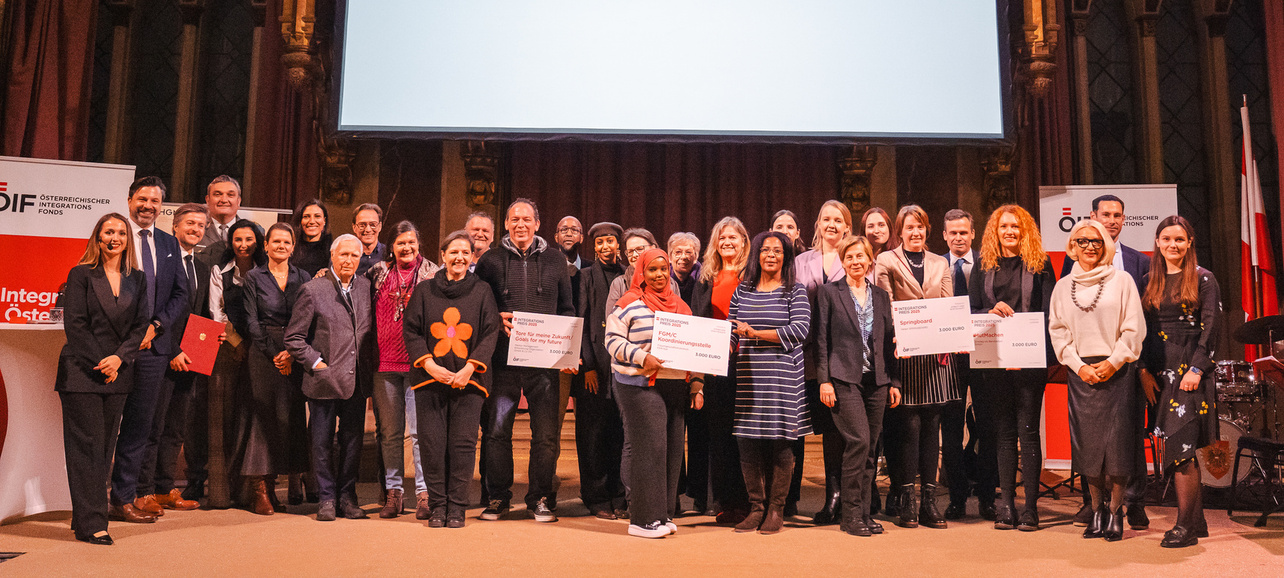 Gruppenfoto von Preisträgern des Integrationspreises 2025 vor einer großen Leinwand mit dem Preisnamen.