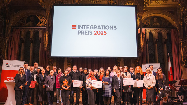Gruppenfoto von Preisträgern des Integrationspreises 2025 vor einer großen Leinwand mit dem Preisnamen.