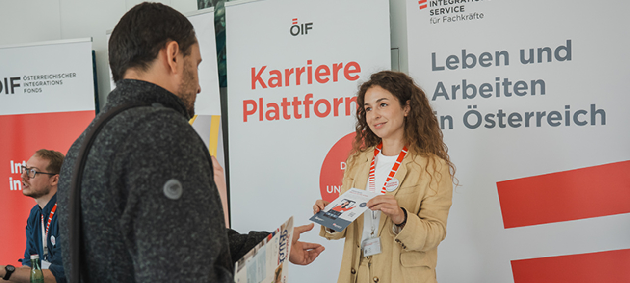 Eine Person erklärt Karrierechancen und verteilt Informationsmaterial an einen Interessierten.