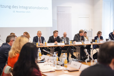 Sitzung des Integrationsbeirats mit verschiedenen Teilnehmern an einem Konferenztisch.
