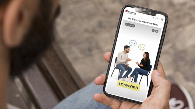 Smartphone zeigt Sprachportal-App mit Gespräch zweier Personen